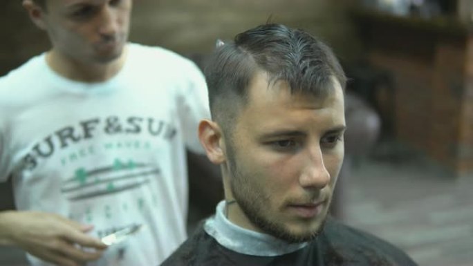 特写大师在理发店剪掉男人的头发和胡须，美发师为一个年轻人做发型
