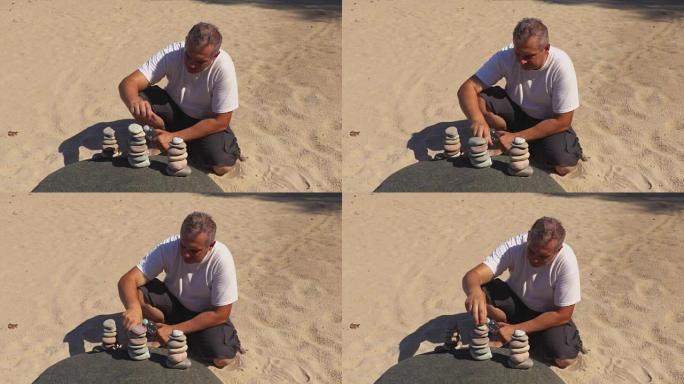 人坐在沙滩上，建造平衡的石头金字塔
