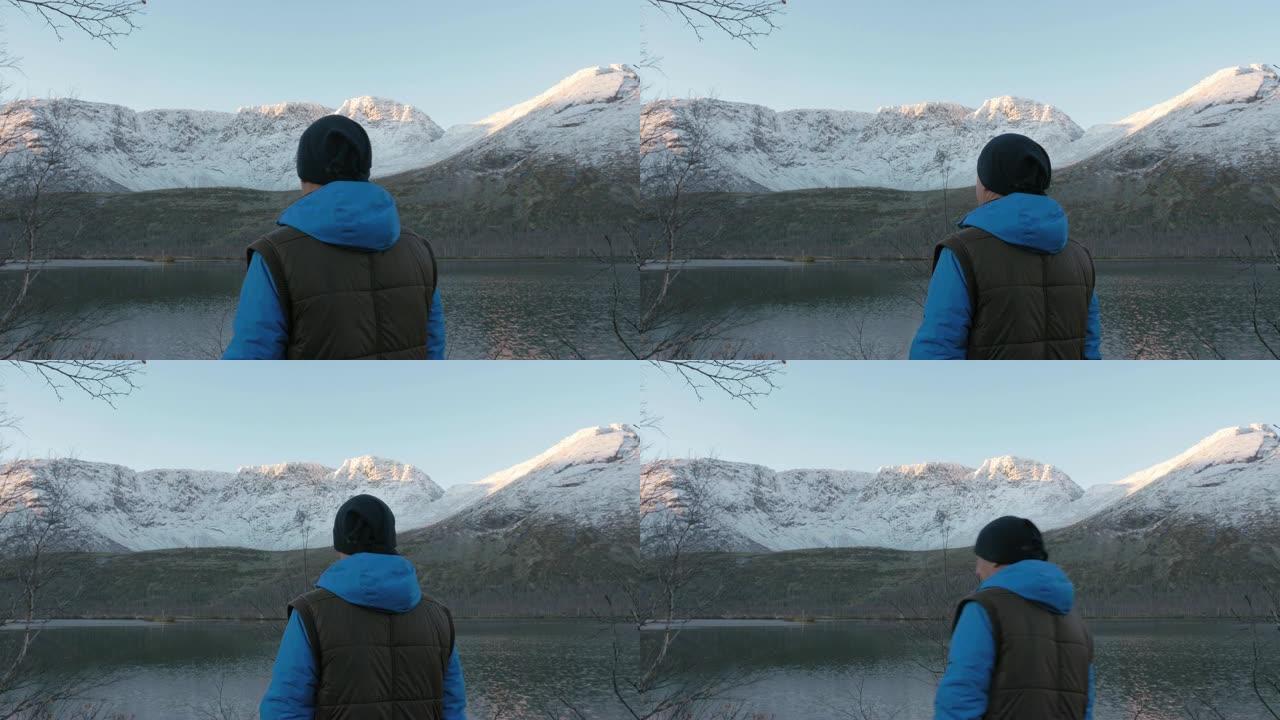 一个男人，一个中年运动员，在山里遇见夕阳。他欣赏太阳和湖中群山的倒影。