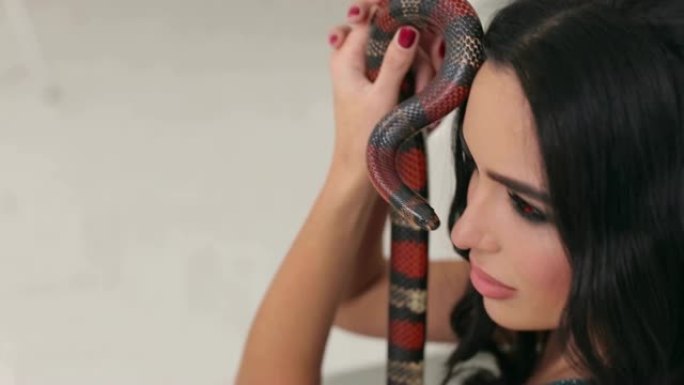 一个专业化妆的女孩的特写镜头手里拿着一条蛇。