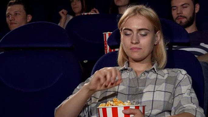 迷人的女性在电影院的电影首映式上吃爆米花