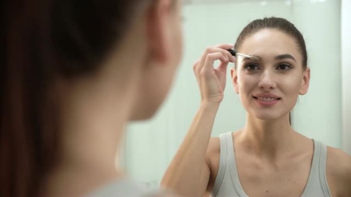 美容化妆。女人在浴室镜子上刷眉毛
