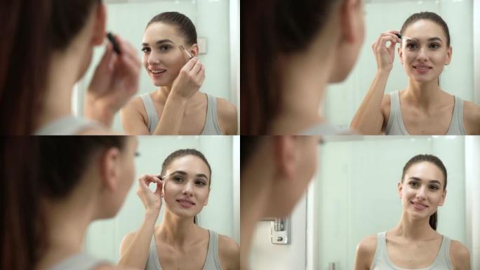 美容化妆。女人在浴室镜子上刷眉毛