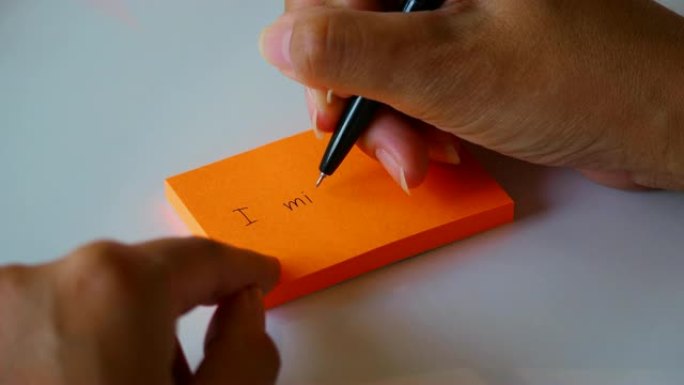 在橙色的贴纸或记事本上手写 “我想念你” 一词。4k素材