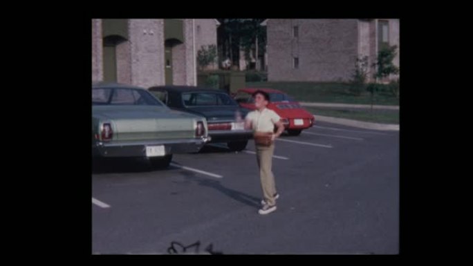 1971小男孩在停车场的空中扔棒球，假货扔给相机