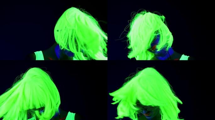 女人的慢动作用UV面部彩绘，假发，发光的衣服肖像摇头。高加索女人。。
