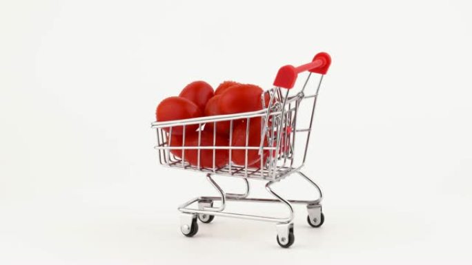 装满红葡萄西红柿的购物车堆满了水滴。在转盘上旋转。孤立在白色背景上。特写。宏观。