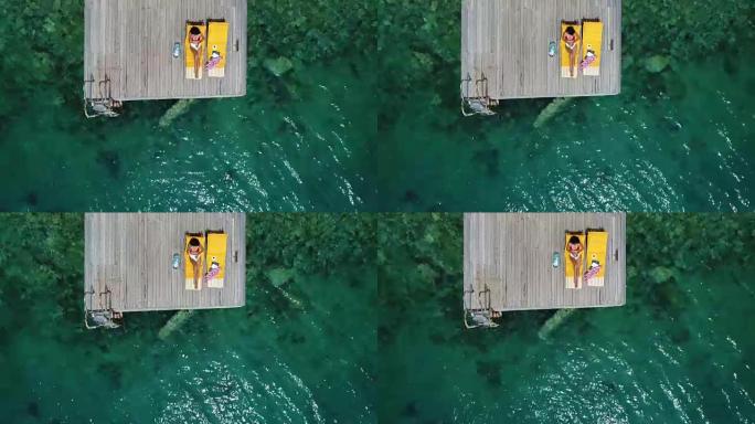 美女独自在木墩上晒日光浴在海上空中4k视频