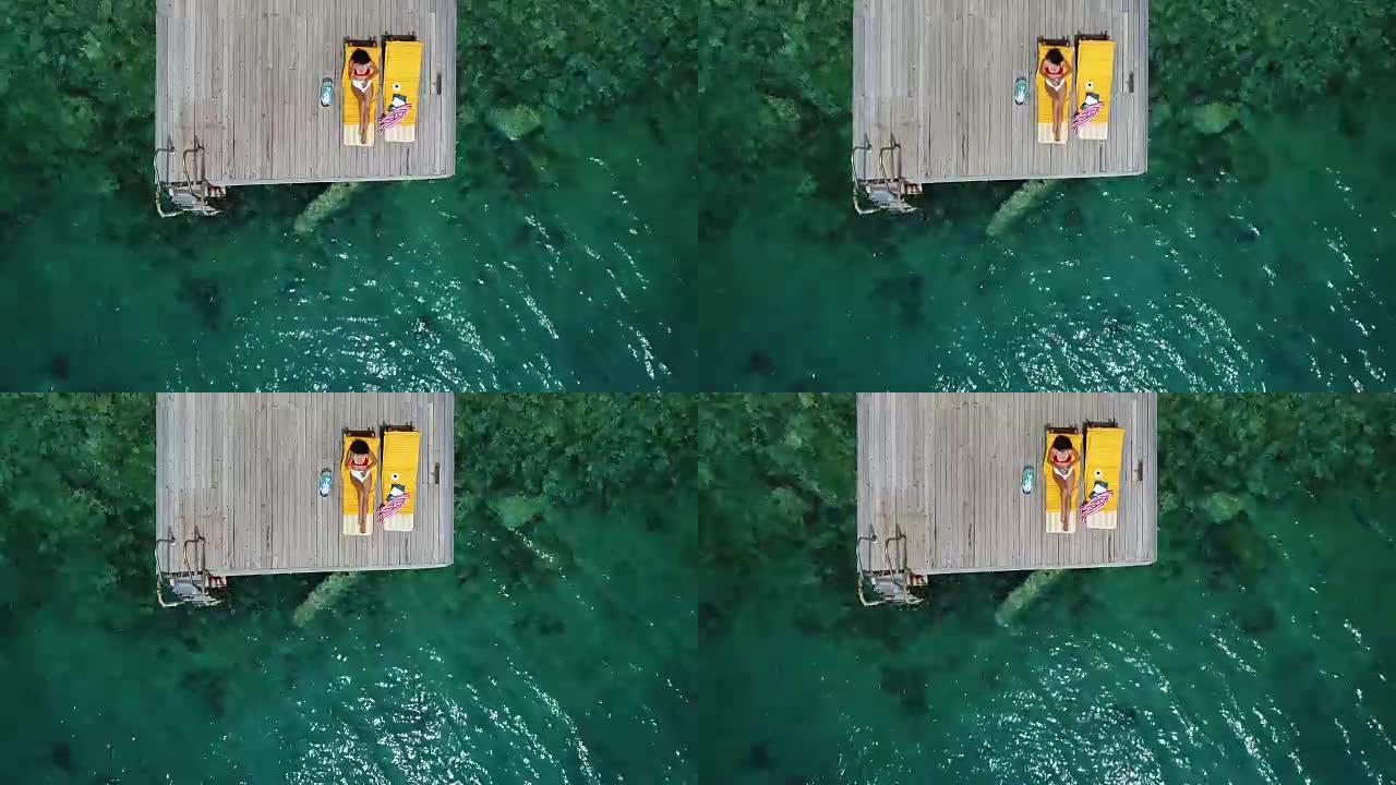 美女独自在木墩上晒日光浴在海上空中4k视频