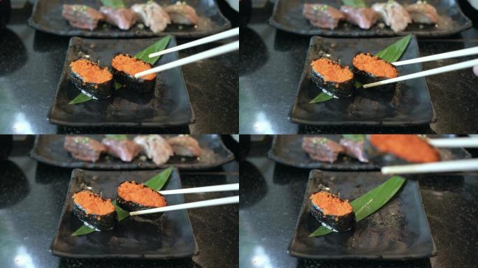 手持筷子拿新鲜飞鱼子寿司的前视图
