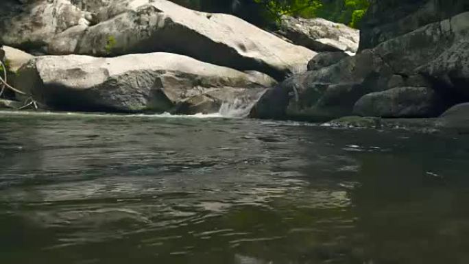 山地雨林景观中的石河。溪河在山瀑布的大石头上流动。美丽的风景野生自然