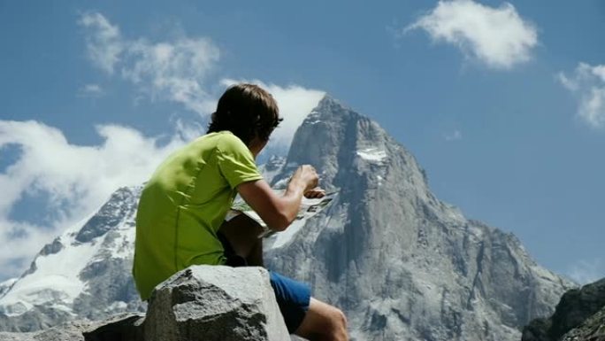 游客徒步旅行者看着地图，在山上研究路线坐在岩石上特写，慢动作