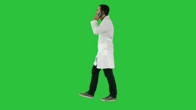 年轻的医生在绿色屏幕上与mobile和walkind交谈，色度键
