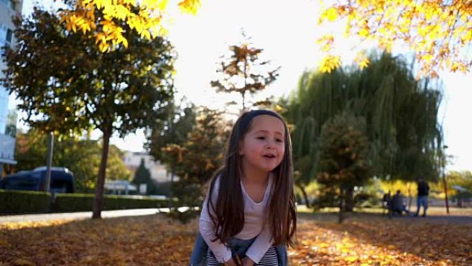 可爱的蹒跚学步的孩子在公园捡树叶扔树叶