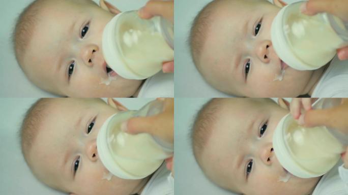 特写妈妈用手从瓶子里喂新生婴儿牛奶。