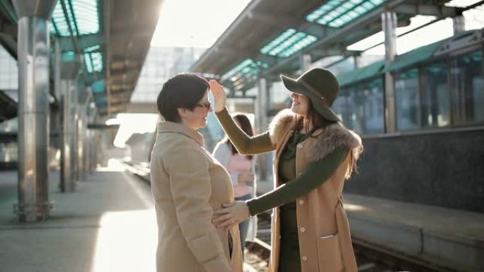 成年妇女护送他的女儿在火车站的月台上。