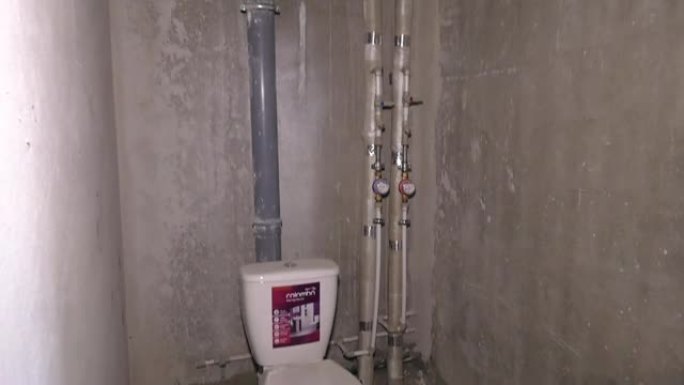 墙壁由聚丙烯制成的水管，房屋中的管道。维修时将污水管安装到马桶上。水表。厕所里的墙壁没有灰泥。废水用