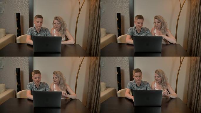 快乐的年轻夫妇一边微笑着看着平板电脑。在家。室内