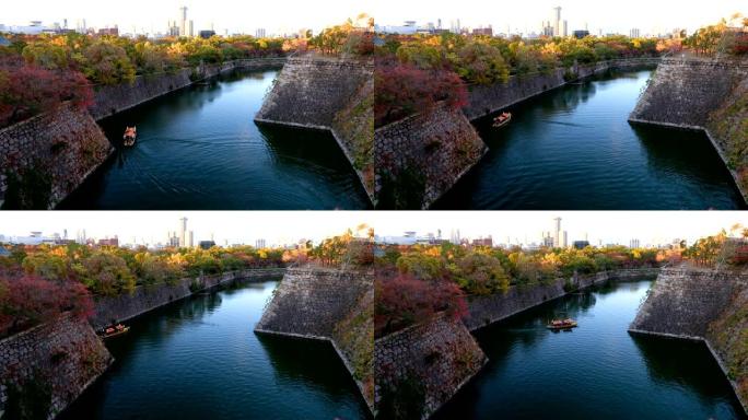 4k慢动作: 古董日本船在现代城和老城墙之间的河上缓缓漂浮