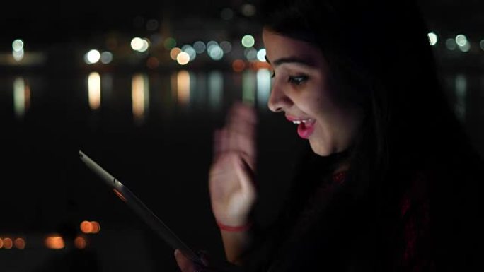 年轻女子视频聊天在平板电脑上谈论微笑挥手拜拜问候欢迎触摸屏信息旅游网在印度教寺庙圣城湖城手持电脑上冲