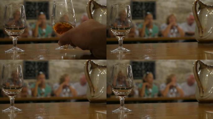在品酒室品酒。在克里米亚酿酒厂周围游览。巴卡利站在桌子上。将酒倒入玻璃盘中。侍酒师把手伸向酒杯。阳光