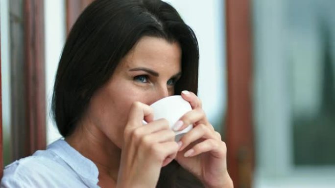 快乐的女性脸喝咖啡或茶手持白瓷杯享受周末