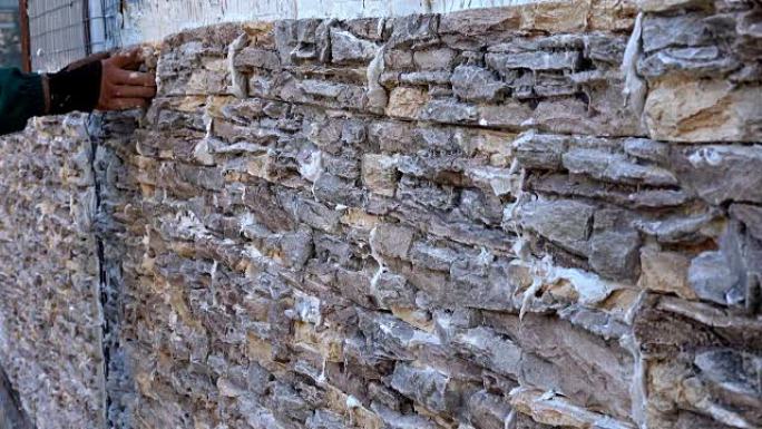 工人用观赏石瓷砖装饰墙壁，将瓷砖牢固地压制并固定成特殊的胶水和水泥混合物