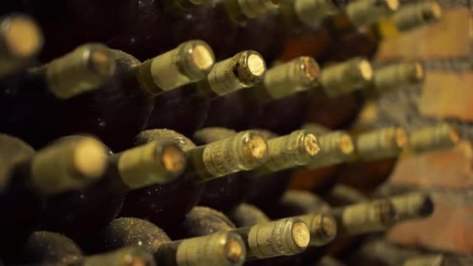 酒窖里满是灰尘的旧酒瓶。葡萄酒的生产。深色酒窖配可收藏的红酒。4K (UHD