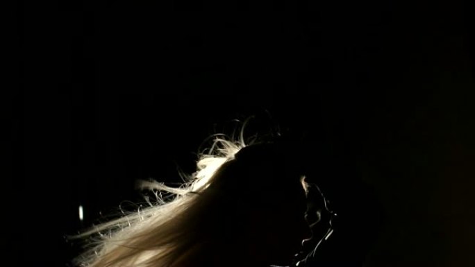 一个美丽的女孩的剪影，在黑暗中轻盈的头发。