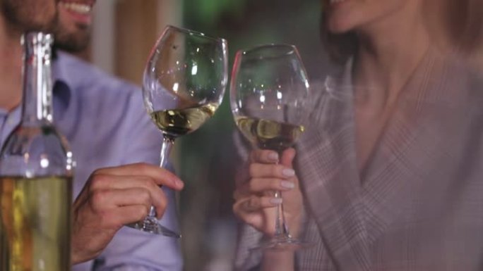 情侣在浪漫的晚餐上用白酒杯欢呼