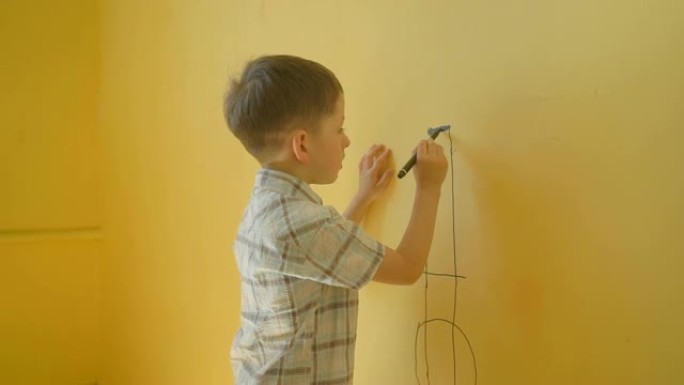 小男孩在家里的黄墙上画画