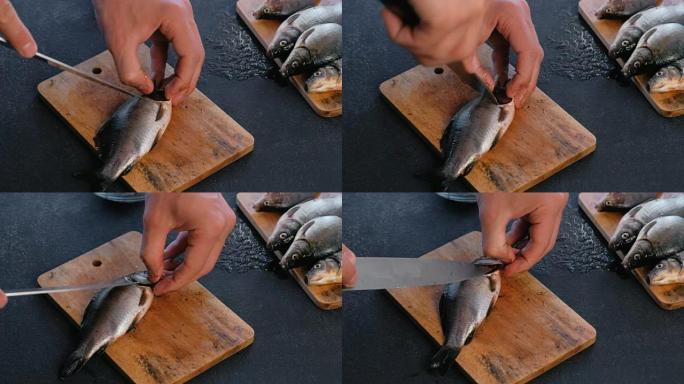 男人切鲤鱼的鳃。煮鱼。双手合拢。