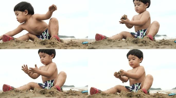 男婴在沙滩上玩沙子玩具