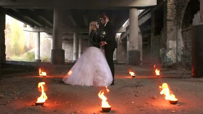 万圣节穿婚纱的情侣肖像，围绕着他们的火燃烧。