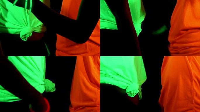 女性的慢动作用UV面部涂料，发光的衣服，发光的手镯，在镜头前跳舞的眼镜，身体拍摄。高加索人和女人。。
