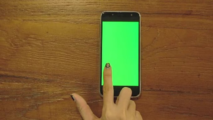 使用带有空白绿色显示屏的智能手机的女性手的俯视图。