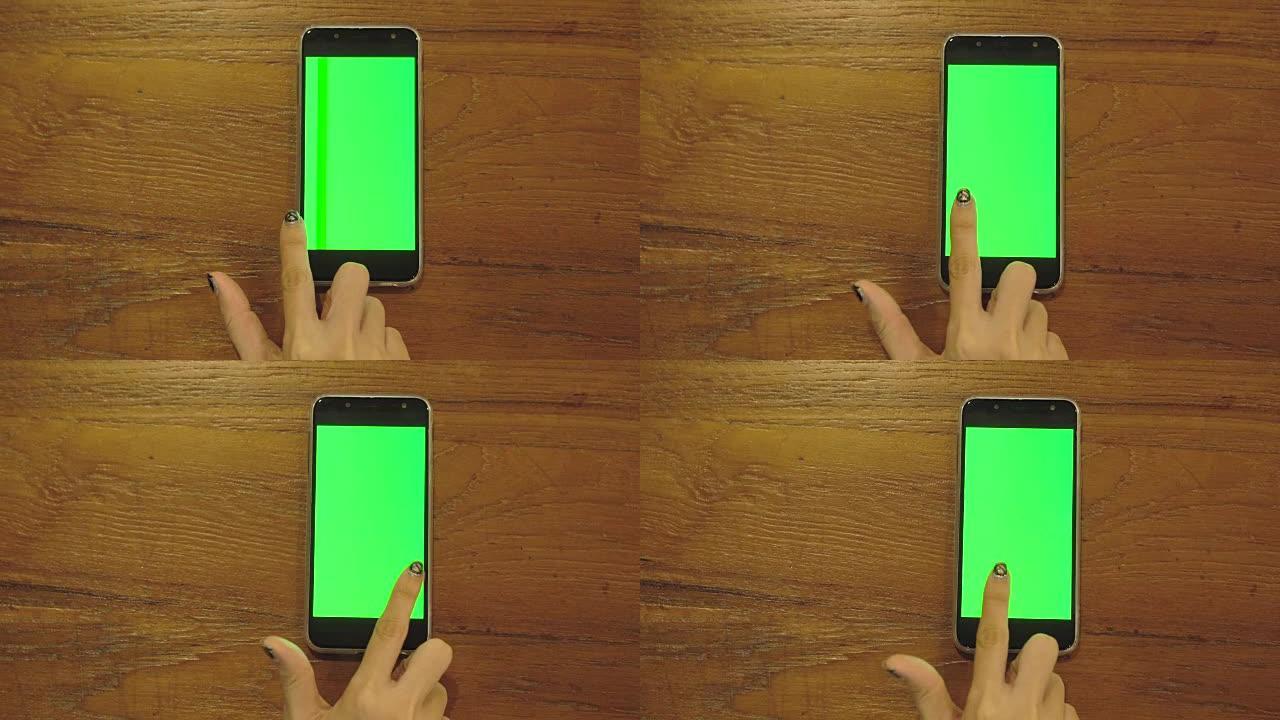 使用带有空白绿色显示屏的智能手机的女性手的俯视图。