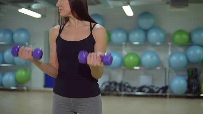 健身概念。年轻的女运动员在健身房用哑铃训练。