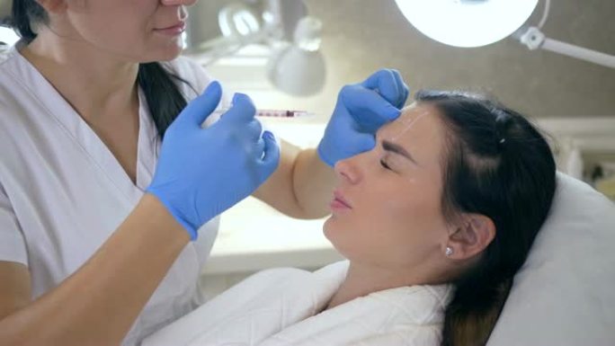医生或美容师在手套为女性在美容诊所进行脸部抗衰老注射
