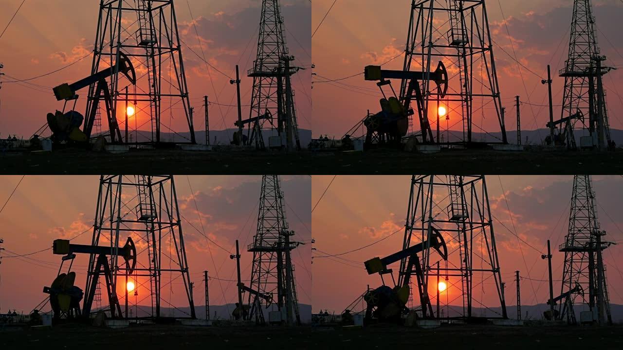 石油井架机构在夕阳下，石油生产。日落时的油泵