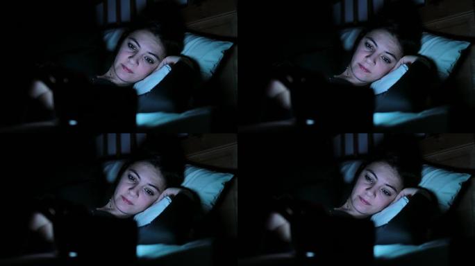 躺在床上的年轻女子带着智能手机。女人在4k睡觉前在手机设备上主演