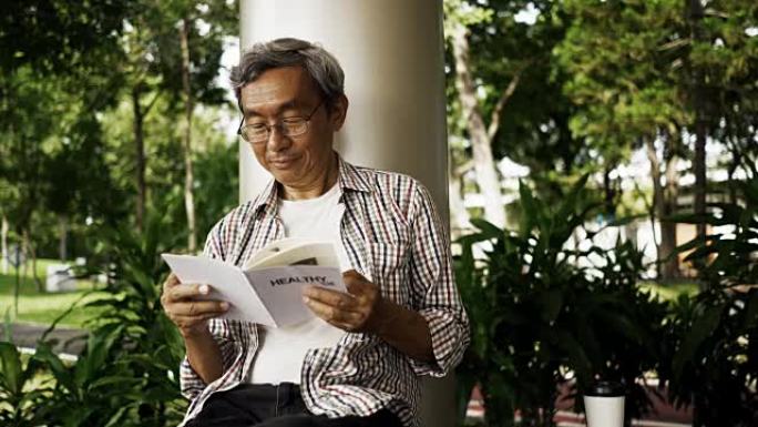 亚洲资深男子独自在公园阅读健康生活书