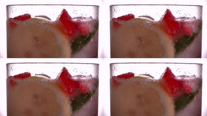 在苏打水中漂浮着草莓，柠檬，酸橙和冰块的水杯关闭