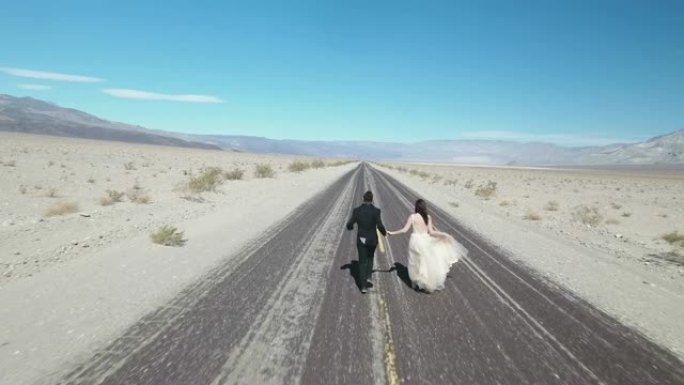 新娘和新郎在美国死亡谷的空旷沙漠路上奔跑