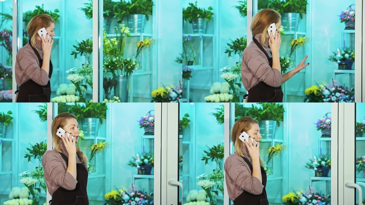 花店的老板在电话里聊天，看着鲜花的陈列柜。