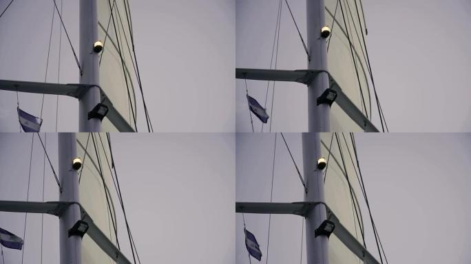 一艘船桅杆的特写镜头，白色的灯光和随风飘扬的船旗。