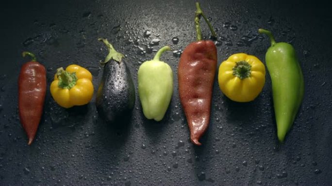 蔬菜，茄子和胡椒在黑暗的表面上滴水