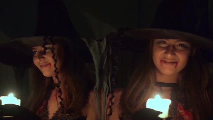 万圣节女巫在镜子附近的黑暗中拿着蜡烛。她在找。