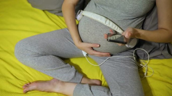 孕妇肚子上拿着耳机