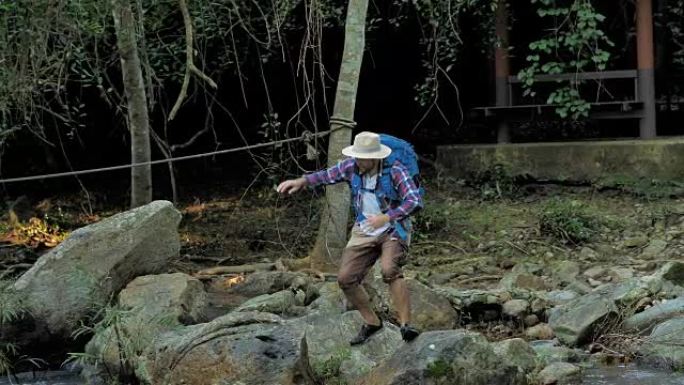冒险家亚洲男人。在森林里的石头上行走和跳跃。冒险和极限旅游，克服障碍。旅行生活方式和成功理念。视频慢